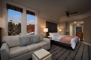 Relax in this serene hotel room with a large bed, sofa, and window offering a view of the surrounding landscape.