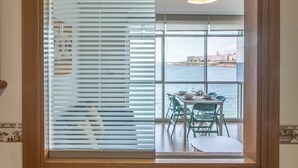 A kitchen with a window overlooking a dining area and a view of the sea.