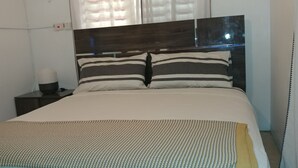 Un lit avec un ensemble d’oreillers à rayures, une lampe de chevet et une couverture à motifs.