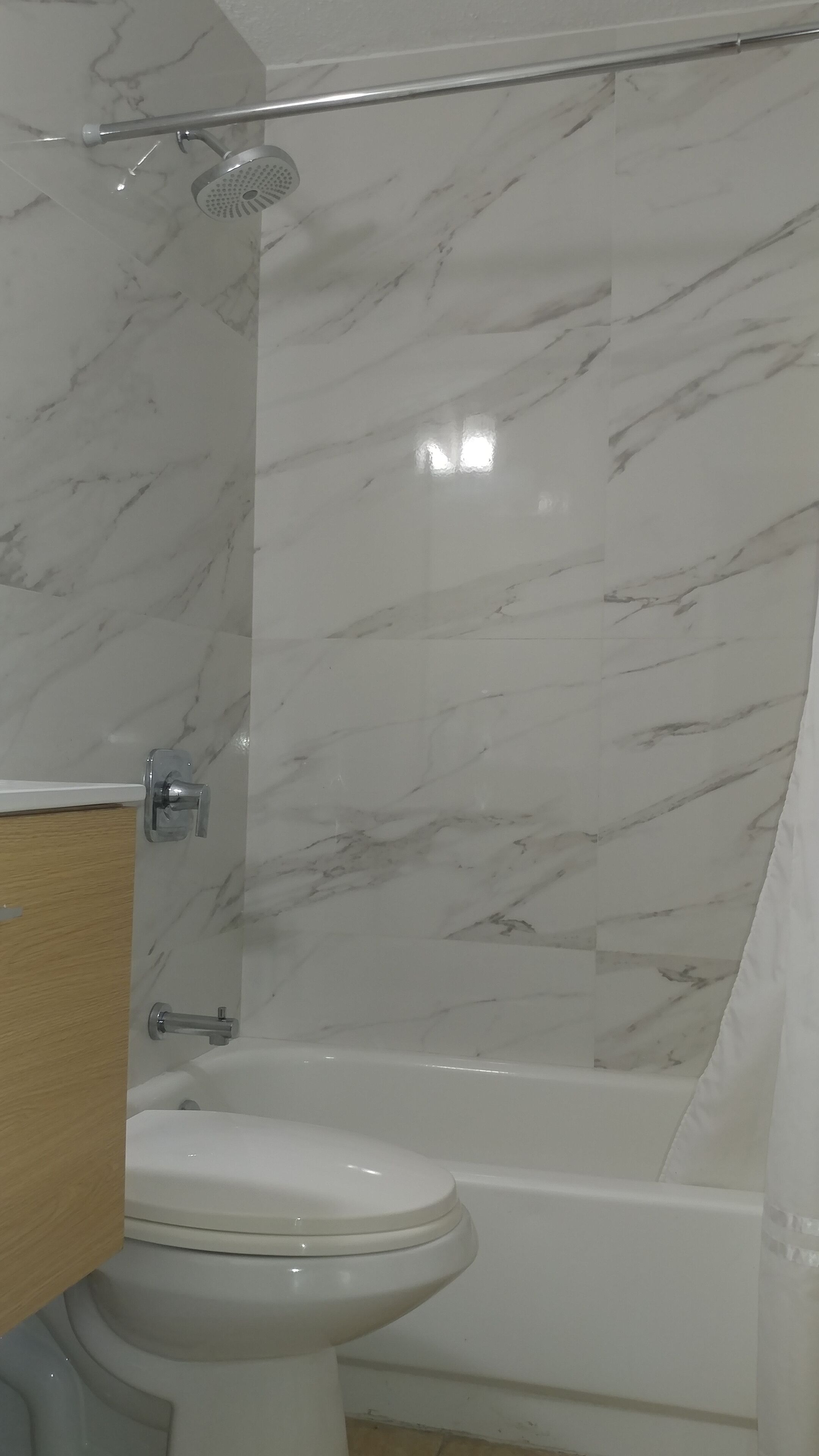 Une salle de bain avec des toilettes blanches, une baignoire et un espace douche.