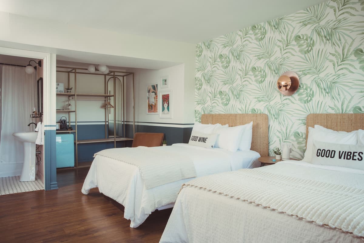 A hotel room with two beds, a bathroom, and a view of the city.
