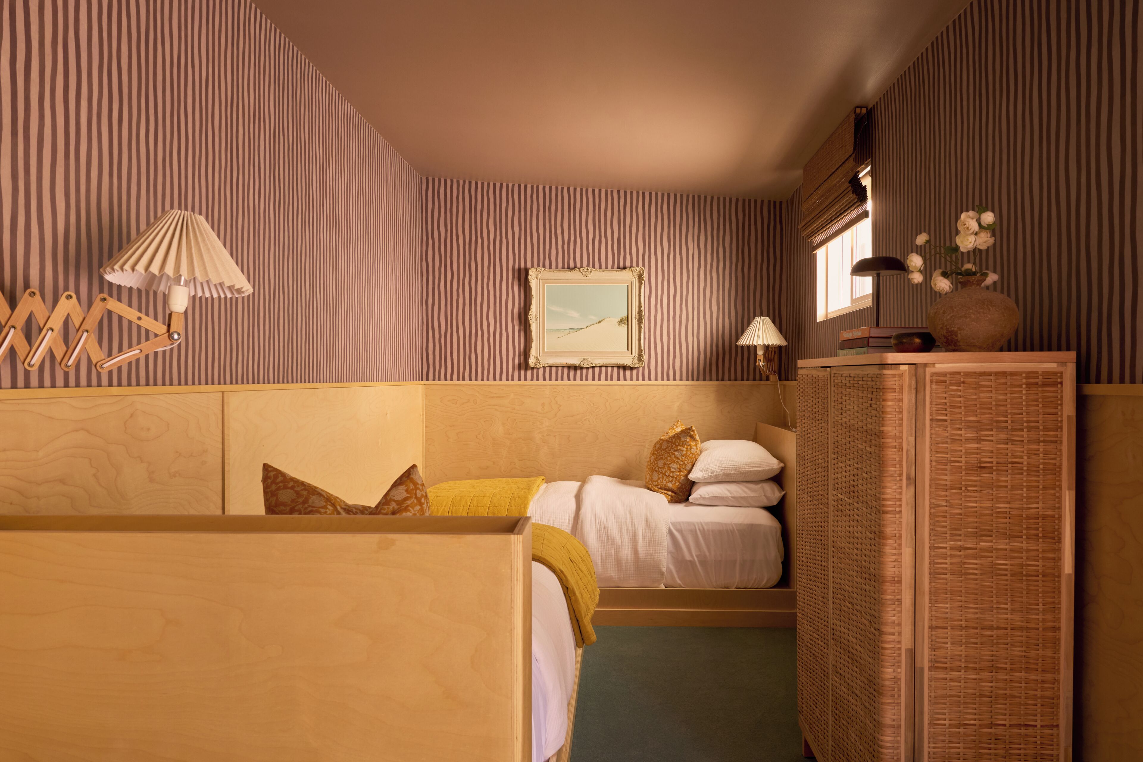 Een kamer met een bed, nachtkastje, lamp, fotolijst en raam.
