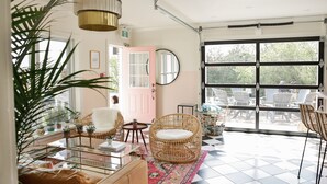 Una habitación con muebles de mimbre, una mesa de centro de vidrio y un ventanal grande.