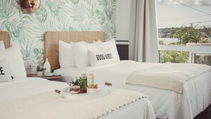 Habitación de hotel con dos camas, un ventanal con vistas al exterior y una pared con diseño de hojas.