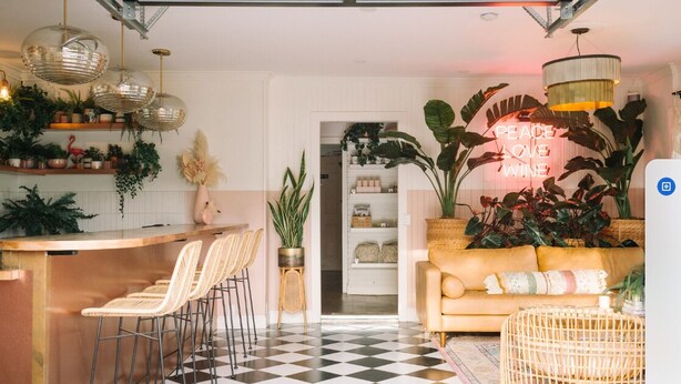 Cocina moderna con barra, comedor y sala de estar con sofá y plantas.