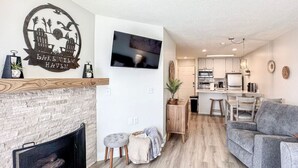 A modern living room with a fireplace, a grey sofa, and a flat-screen TV mounted on the wall. - Inn Building Condo #209-Beautifully updated, view of Bear Lake (Garden City)