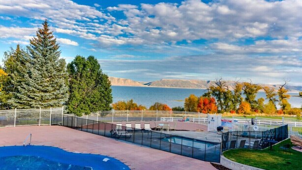 A pool area with a glass enclosure, seating, and a view of a lake and mountains. - Inn Building Condo #209-Beautifully updated, view of Bear Lake (Garden City)