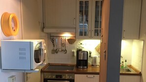 Une cuisine de taille réduite, avec des meubles blancs, un four à micro-ondes, une machine à café et un évier.