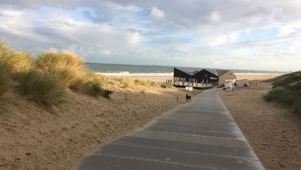 Une promenade en bord de mer qui mène à un bâtiment offrant une vue sur la plage.