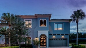 A modern two-story house with a well-maintained lawn, a garage, and a large arched entrance. - Built For Vacation | South-Facing, Large Screen Pool, Splash Pad, Game,Movie Room (Four Corners)