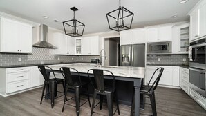 A modern kitchen with white cabinets, a central island with bar stools, stainless steel appliances, and geometric pendant lighting. - Stay awhile and RELAX at Lake Keowee, Clemson and the mountains!
The 5 Seasons (West Union)