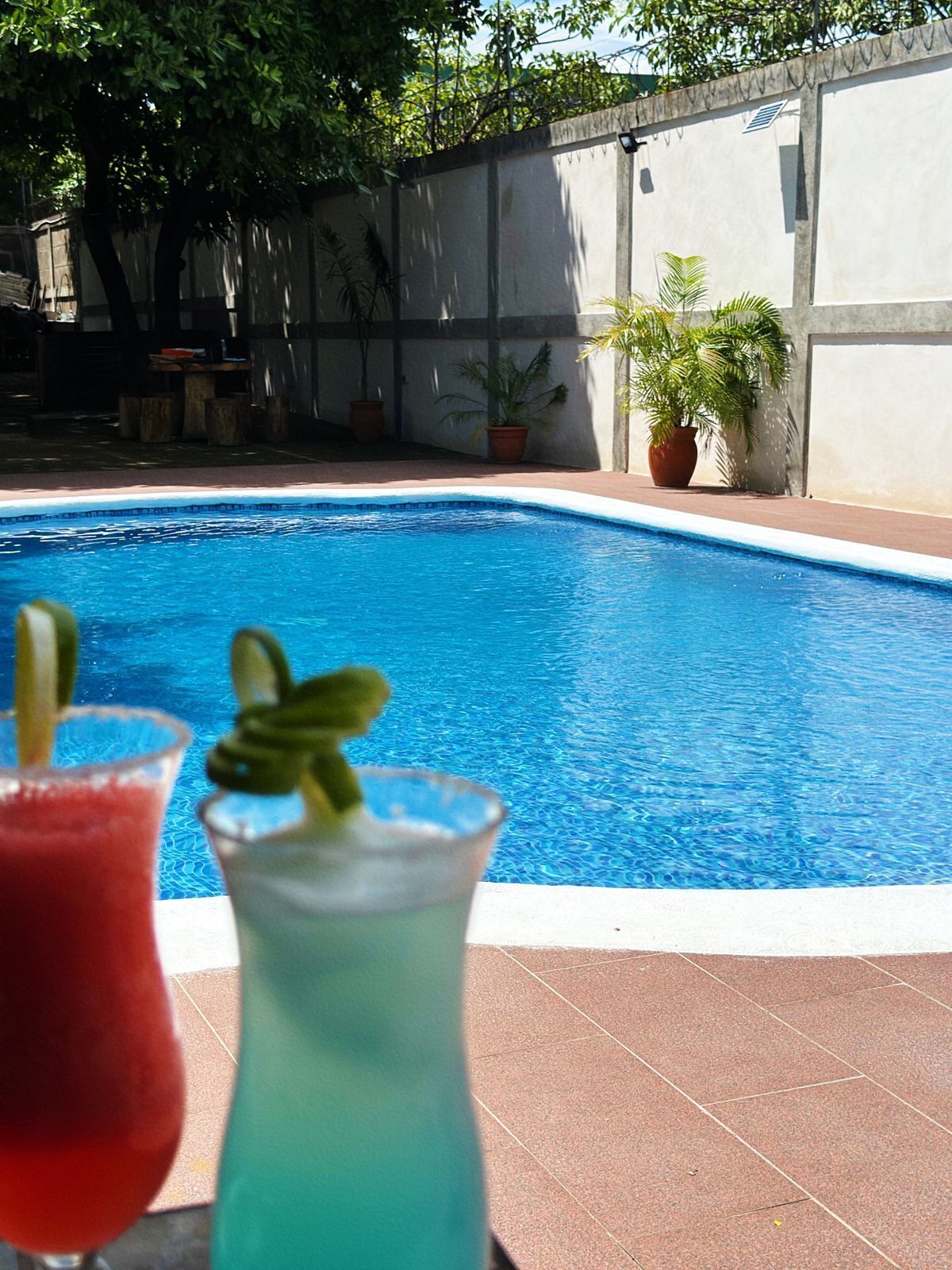 Una piscina con dos bebidas al frente.