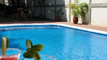 Una piscina con dos bebidas al frente.