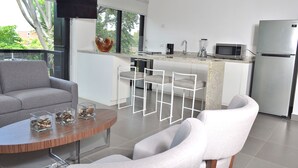 Een moderne keuken met een flatscreen-tv, een magnetron en een koelkast. Er is een eethoek met een ronde tafel en twee stoelen.