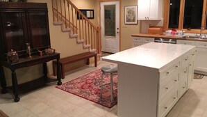 A kitchen with a central island, wooden staircase, and white cabinetry. - Gorgeous Mountain View 8 miles from Appalachian Trail (Roan Mountain)