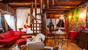 L’intérieur d’un chalet chaleureux, avec un escalier en bois, un coin repas et un salon doté de canapés rouges et d’un fauteuil blanc.