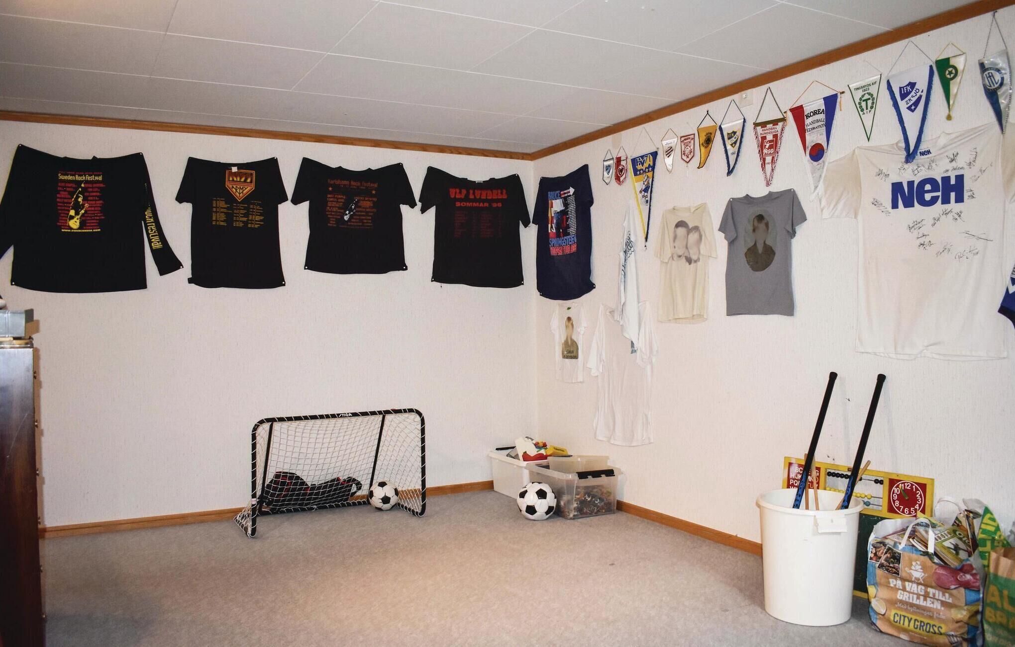 Una habitación con un arco de fútbol, varias camisetas en la pared y un cubo con productos de limpieza.