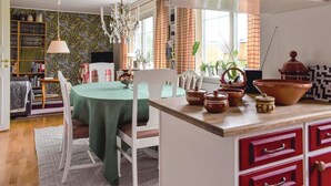 Un comedor acogedor con una mesa verde, sillas blancas y una encimera de cocina con armarios rojos y cerámica.