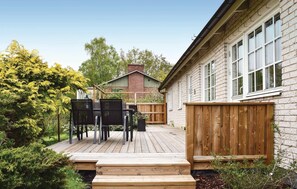 A wooden deck with a table and chairs, a brick house with windows, and a wooden fence. - 3 bedroom cozy home in Karlshamn (Karlshamn)