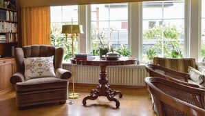Una sala acogedora con un sillón marrón, una mesa de centro de madera y un cojín decorativo.