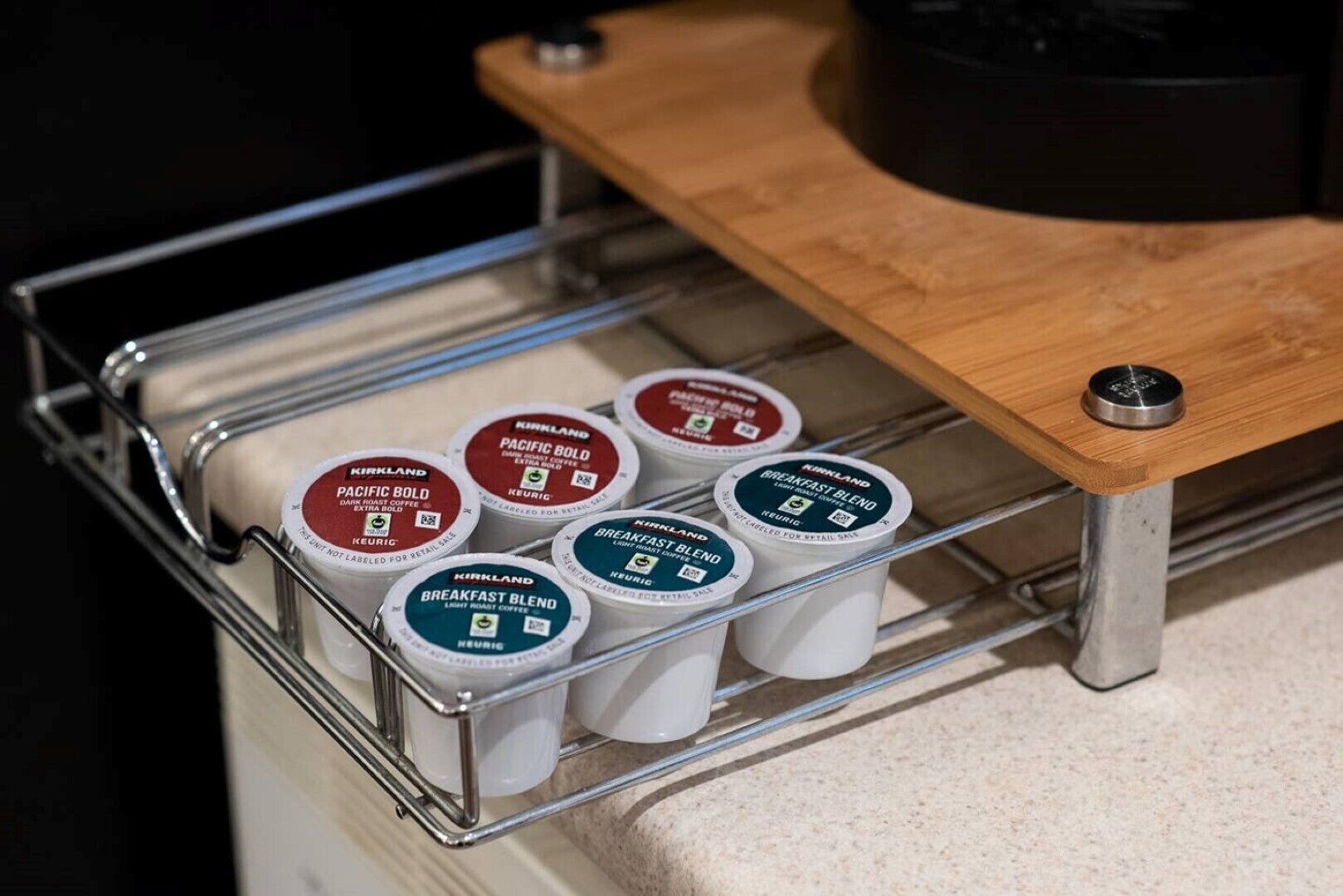 A coffee machine with a metal tray holding several coffee pods labeled 'Kirkland Breakfast Blend'.
