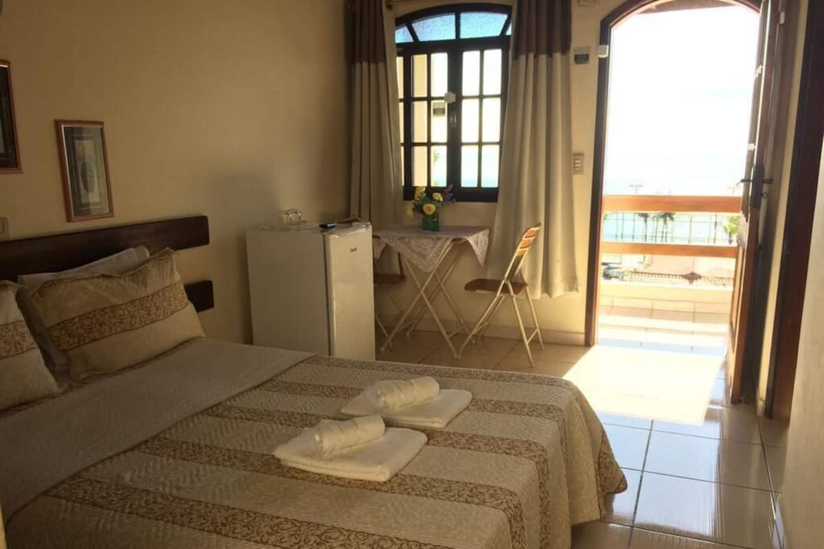 Habitación de hotel con una cama grande, un escritorio y un balcón.