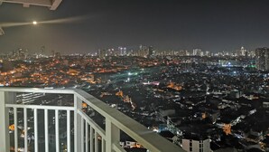 Une vue nocturne sur une ville, prise depuis un balcon doté d’une balustrade.