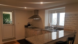 A modern kitchen with granite countertops, a stainless steel sink, and a large window providing natural light. - Carmo Apartment in the center of Espinho (Espinho)