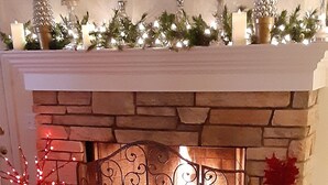 A fireplace with a stone mantle, a decorative metal grate, and a Christmas tree on the mantel. - 3,200SF Home/ 3.5 Bathrooms-3 Showers/Wrap Around Porch/Walk to Town/Beach (Harbor Springs)
