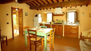 A cozy kitchen with wooden cabinets, a dining table, and chairs. There is a refrigerator, a stove, and a sink. - Borgo del Sole Agriturismo (San Romano in Garfagnana)