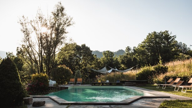 A rectangular swimming pool with a surrounding deck, lounge chairs, and a canopy. - Borgo del Sole Agriturismo (San Romano in Garfagnana)