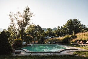 A rectangular swimming pool with a surrounding deck, lounge chairs, and a canopy. - Borgo del Sole Agriturismo (San Romano in Garfagnana)