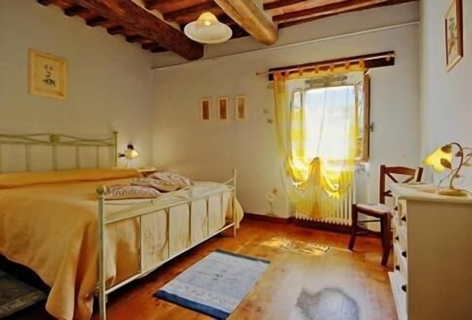 Une chambre à coucher avec un lit, une chaise, un bureau et une fenêtre avec des rideaux.