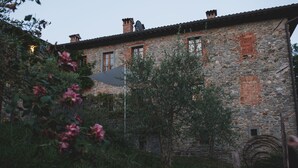 A stone building with multiple windows and a chimney. - Borgo del Sole Agriturismo (San Romano in Garfagnana)