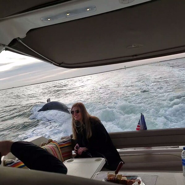 A boat interior with a person holding a camera, a table with a bottle, and a view of the ocean.