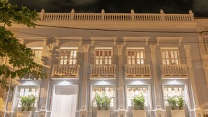 Un bâtiment de style colonial, doté de nombreux balcons et de grandes fenêtres, illuminé la nuit.