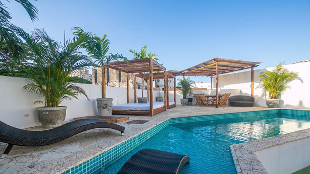 Un espace piscine aménagé sur le toit, avec des chaises longues, une pergola et des plantes en pot.