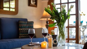 Una mesa redonda con dos copas de vino, una vela y un florero con tulipanes blancos.