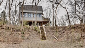 A house with a wooden staircase leading to a deck.