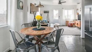 A dining area with a round wooden table, metal chairs, and a vase of yellow flowers.