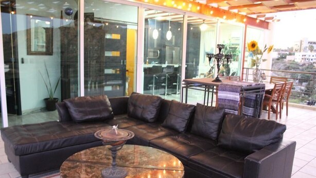 A modern living room with a leather sectional sofa, a round coffee table, and a dining area with a table and chairs.