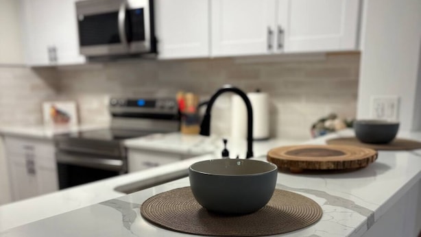 A modern kitchen with white cabinets, a microwave, and a stainless steel oven.