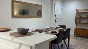 A modern dining area with a white island, dark chairs, and a wooden sideboard.