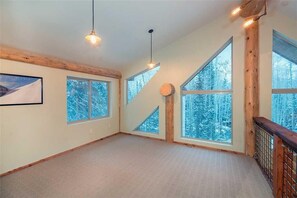 A spacious room with large windows, wooden beams, and a simple carpeted floor. - FOX Farm Retreat (Telluride)