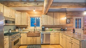 Eine Küche mit Holzausstattung, Edelstahlgeräten und einer Arbeitsplatte aus Granit.