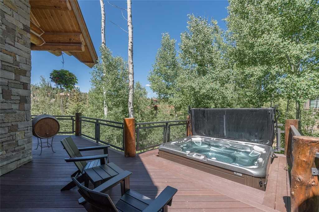 Eine Holzterrasse mit Whirlpool, Sitzgelegenheiten im Freien und einer Steinwand.