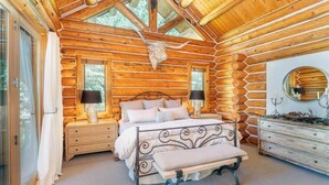 Une chambre située dans une cabane en rondins, avec un lit, des tables de chevet, un banc et une commode.