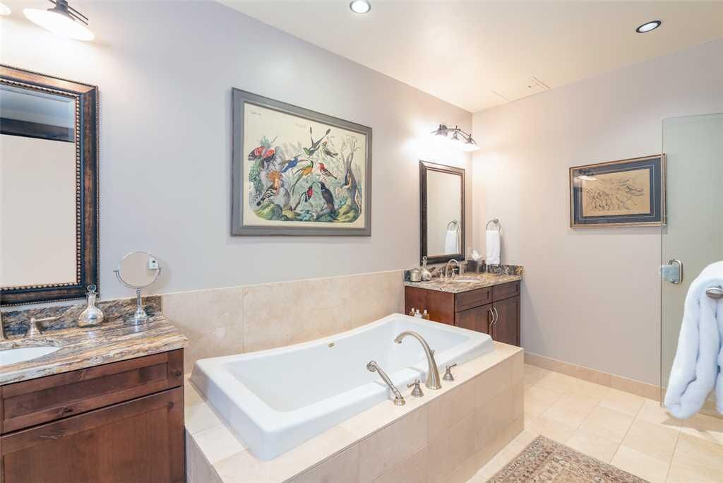 A modern bathroom with a large bathtub, two sinks, and a vanity with a mirror.