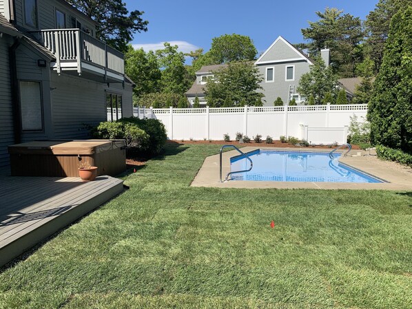 Un jardin avec une piscine, un jacuzzi et une terrasse en bois.