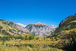 A mountainous landscape with a lake and a small house in the foreground. - Riverside B02 (Telluride)